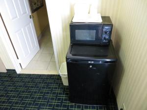 Un four micro-ondes est installé au-dessus d'un réfrigérateur noir. dans l'établissement Budget Inn Hollywood, à Los Angeles