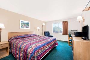a hotel room with a bed and a flat screen tv at Super 8 by Wyndham Belle Fourche SD in Belle Fourche