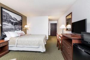 a hotel room with a bed and a flat screen tv at Super 8 by Wyndham Kalispell Glacier National Park in Kalispell