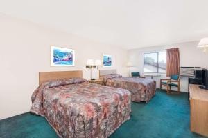 a hotel room with two beds and a desk at Super 8 by Wyndham Belle Fourche SD in Belle Fourche
