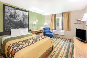 a hotel room with a bed and a television at Super 8 by Wyndham Grayling in Grayling