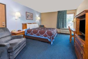 a hotel room with a bed and a couch and a television at Super 8 by Wyndham O'Fallon MO/St. Louis Area in O'Fallon