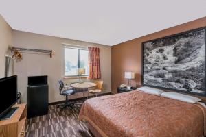 a hotel room with a bed and a flat screen tv at Super 8 by Wyndham Madison in Madison