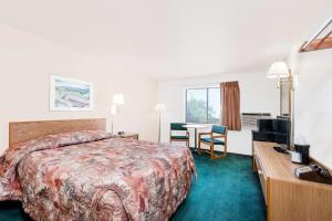 ein Hotelzimmer mit einem Bett, einem Schreibtisch und einem TV in der Unterkunft Super 8 by Wyndham Belle Fourche SD in Belle Fourche