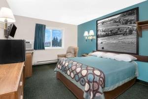 a hotel room with a bed and a flat screen tv at Super 8 by Wyndham Huron in Huron