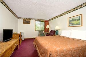 a hotel room with a bed and a flat screen tv at Super 8 by Wyndham Chaska in Chaska