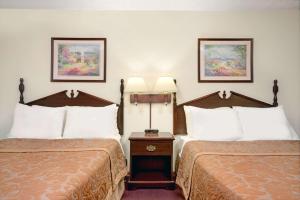 ein Hotelzimmer mit 2 Betten und einem Tisch in der Unterkunft Super 8 by Wyndham Chaska in Chaska