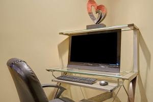 a desk with a computer monitor and a chair at Super 8 by Wyndham Melrose in Melrose