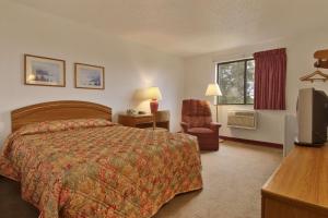 a hotel room with a bed and a chair and a television at Super 8 by Wyndham New Castle in New Castle