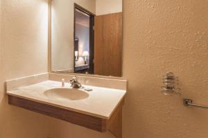 Super 8 by Wyndham Hartford WI في Hartford: حمام مع حوض ومرآة