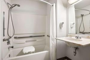 a white bathroom with a tub and a sink at Brookville Inn in Brookville