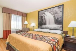 a hotel room with a bed with a waterfall painting on the wall at Super 8 by Wyndham Rice Lake in Rice Lake