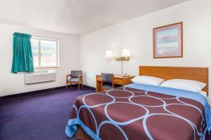 a hotel room with a bed and a desk and a window at Super 8 by Wyndham Sidney NY in Sidney