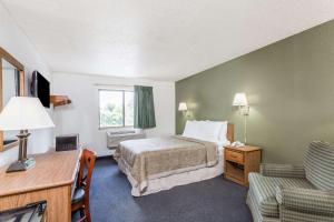 a hotel room with a bed and a desk and chair at Super 8 by Wyndham Hampton in Hampton