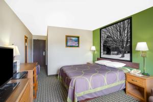 um quarto de hotel com uma cama e uma televisão de ecrã plano em Super 8 by Wyndham Radford VA em Radford