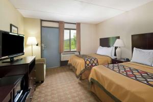 a hotel room with two beds and a flat screen tv at Super 8 by Wyndham White River Junction in White River Junction