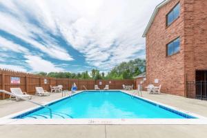 a swimming pool with patio furniture and a brick building at Super 8 by Wyndham Georgetown in Georgetown