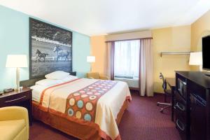 a hotel room with a bed and a television at Super 8 by Wyndham Richmond in Richmond