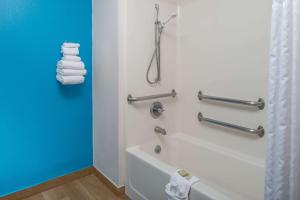 a bathroom with a tub and a shower with towels at Super 8 by Wyndham Lincoln West in Lincoln