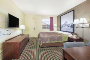 a hotel room with a bed and a flat screen tv at Super Stay Inn And Suites in Muskogee