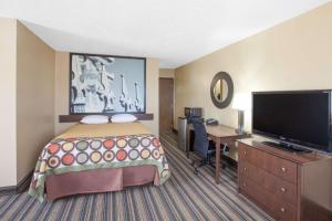 Super 8 by Wyndham Natchitoches في نتشتوشس: غرفة في الفندق بها سرير ومكتب وتلفزيون بشاشة مسطحة
