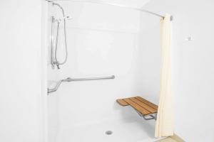 a shower with a wooden bench in a bathroom at Super 8 by Wyndham Howe in Howe