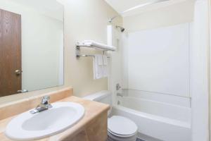 a bathroom with a sink and a toilet and a mirror at Super 8 by Wyndham Buffalo in Buffalo +30 photos