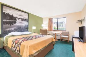 a hotel room with a bed and a desk and a television at Super 8 by Wyndham Buffalo in Buffalo