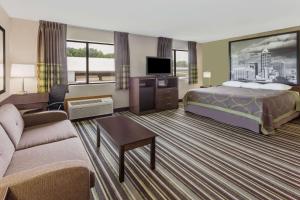a hotel room with a bed and a couch at Super 8 by Wyndham Plymouth in Plymouth
