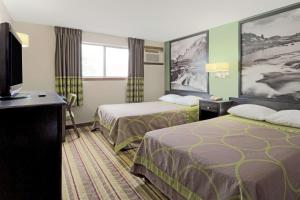a hotel room with two beds and a flat screen tv at Super 8 by Wyndham Green River in Green River