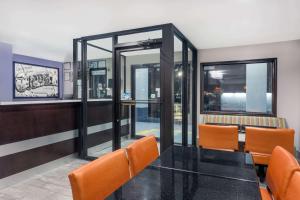 a dining room with a glass table and orange chairs at Super 8 by Wyndham Locust Grove in Locust Grove