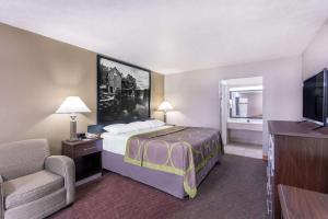 una camera d'albergo con letto e sedia di Super 8 by Wyndham Locust Grove a Locust Grove