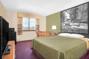 a hotel room with a bed and a large window at Super 8 by Wyndham Riverton in Riverton