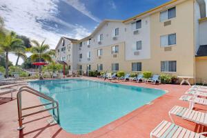 una piscina con sillas y un hotel en Super 8 by Wyndham Clearwater/St. Petersburg Airport, en Clearwater