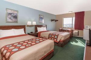a hotel room with two beds and a desk at Super 8 by Wyndham Woodstock in Woodstock