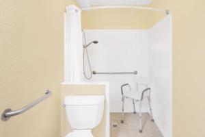 a bathroom with a toilet and a chair at Super 8 by Wyndham Kerrville TX in Kerrville +26 photos