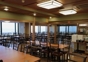 Un comedor con mesas y sillas y ventanas. en Uomisaki Hotel, en Atami