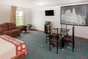 a hotel room with a bed and a table and a couch at Super 8 by Wyndham Pekin/Peoria Area in Pekin