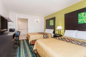 a hotel room with two beds and a flat screen tv at Super 8 by Wyndham Augusta in Augusta