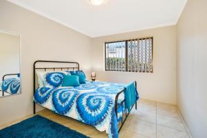una camera con un letto blu e una finestra di Woomba1 a Mooloolaba