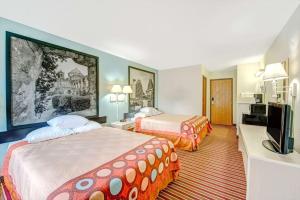 a hotel room with two beds and a flat screen tv at Super 8 by Wyndham San Antonio/Fiesta in San Antonio