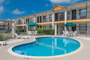 a pool with chairs and umbrellas in front of a building at Days Inn Windcrest by Wyndham San Antonio in San Antonio