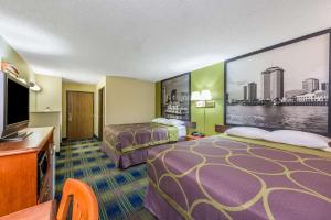 a hotel room with two beds and a flat screen tv at Super 8 by Wyndham Sulphur Lake Charles in Sulphur
