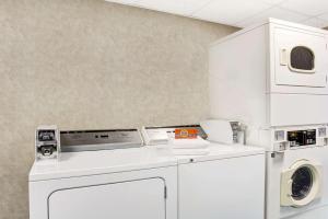 a white laundry room with a washer and dryer at Days Inn by Wyndham Newport News City Center Oyster Point in Newport News