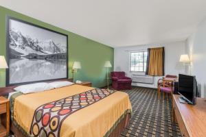 a hotel room with a bed and a flat screen tv at Super 8 by Wyndham Coshocton Roscoe Village in Coshocton