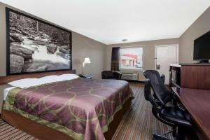 a hotel room with a bed and a desk and chairs at Super 8 by Wyndham Chattanooga Ooltewah in Ooltewah