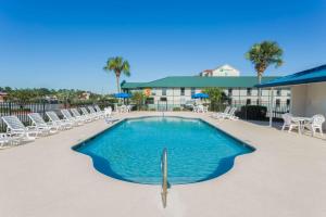 a large swimming pool with chairs and a building at Super 8 by Wyndham Valdosta GA I-75 in Valdosta