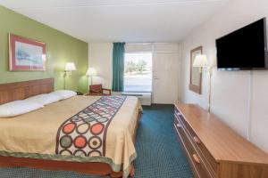 a hotel room with a large bed and a flat screen tv at Super 8 by Wyndham Tifton in Tifton