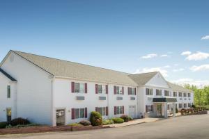 a large white building with red windows on a street at Super 8 by Wyndham Webster/Rochester in Webster