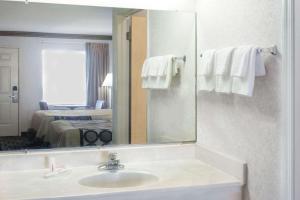 ein Badezimmer mit Waschbecken und Spiegel in der Unterkunft Super 8 by Wyndham Ashburn in Ashburn + 16 Fotos